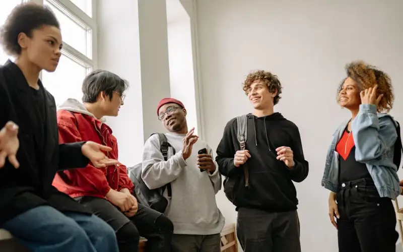 A diverse group on young people talk casually in a school hallway.