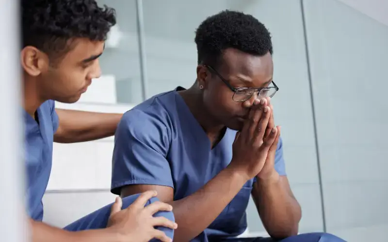 A multiracial young person comforts another Black young person in a show of support.