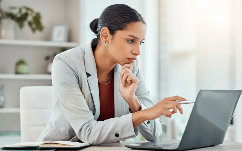 A woman who is a mental health professional studies a laptop screen.