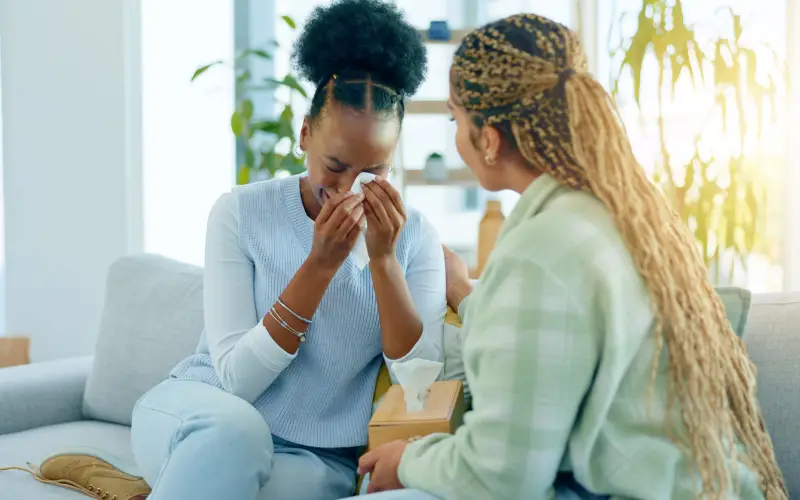 A young Black woman cries during a therapy session.