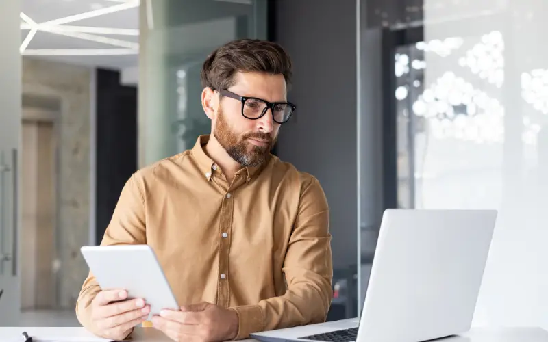 A professional White man uses a laptop to search for information.