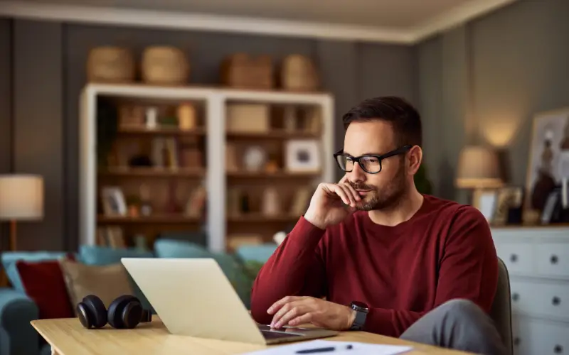 A young White man uses a laptop to search for information.