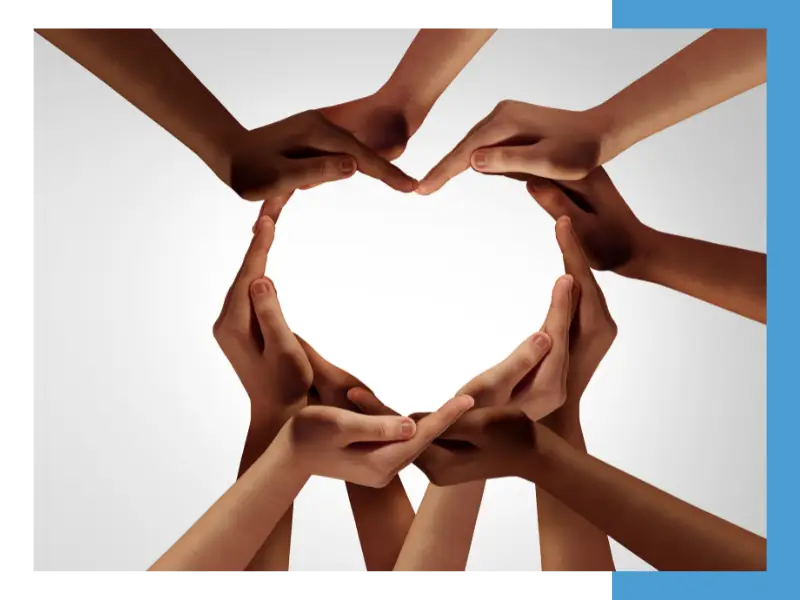 An image of people joining hands to create the shape of a heart, looking from below.