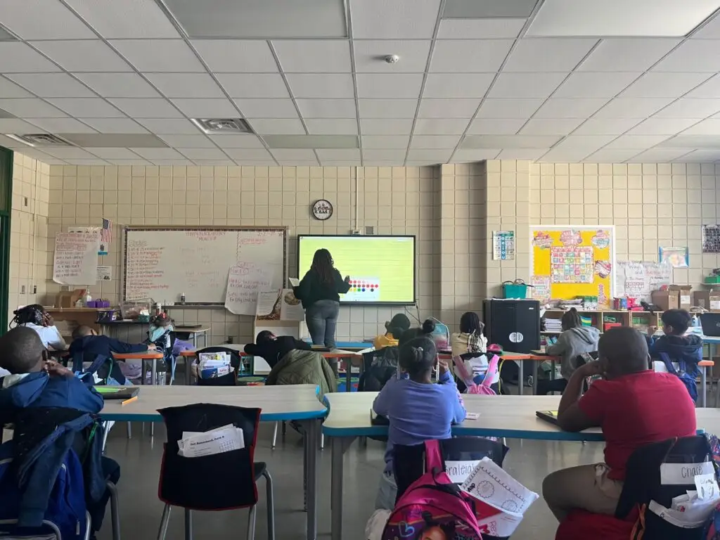 An educator presenting to young students in a classroom.