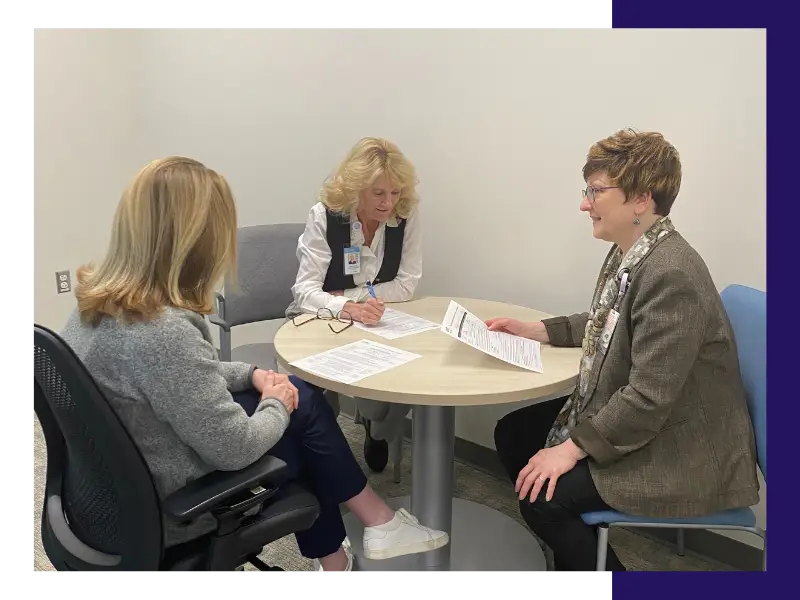 Three members of the program team sitting at a conference table talking.